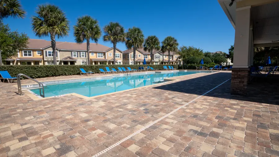 Community pool lined with palm trees and lounge chairs